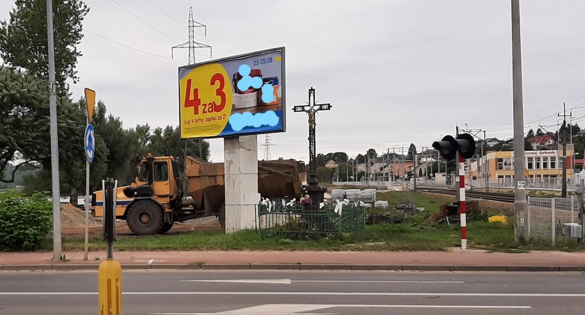 Na zdjęciu: reklama tuż obok zabytkowego krzyża
