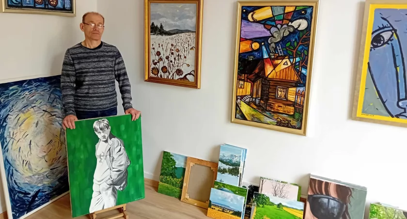 Czesław Kotwica ze swoim autoportretem, który promuje wernisaż wystawy na otwarcie Galerii 
