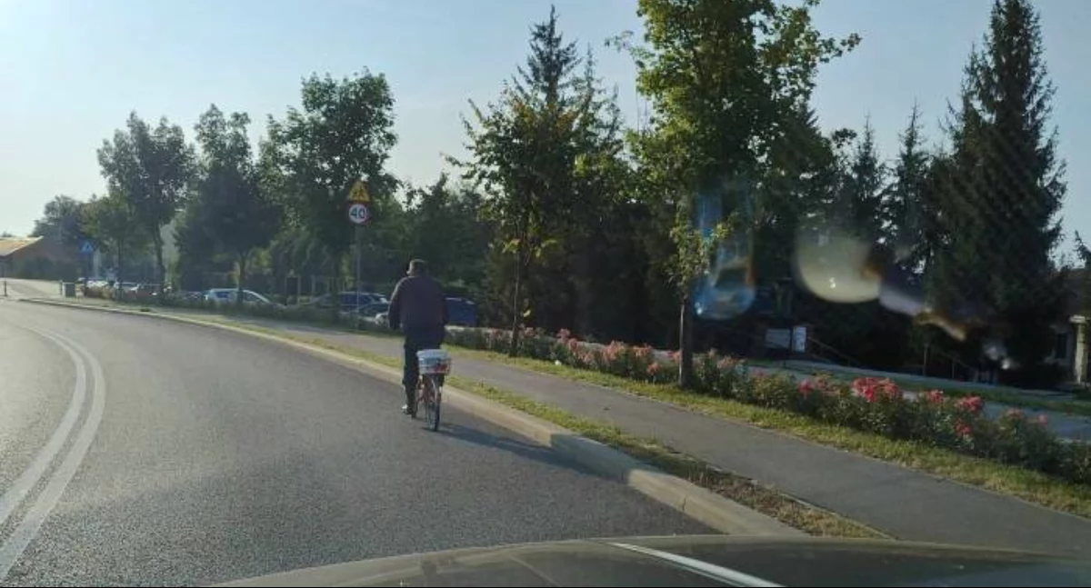 ROwerzysta jedzie ulica a obok ścieżka rowerowa