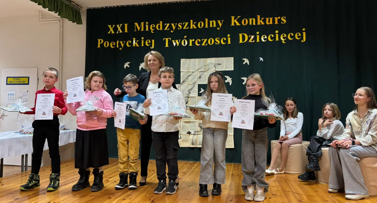 Bożena Jaskros z nagrodzonymi uczestnikami konkursu. Siedzą dziewczęta z SP STO recytujące i śpiewające